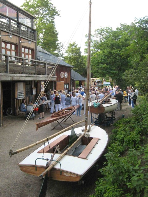 foule en marinières et canotiers devant l'atelier de Sequana, avec au premier plan le monotype de Chatou, l'hirondelle Sequana et un canoë français